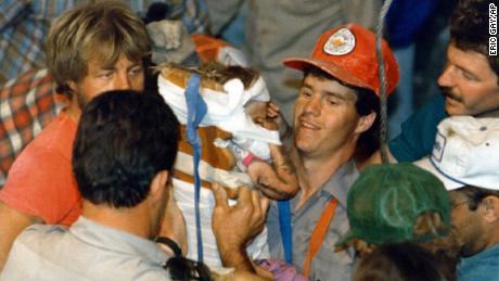 Rescue worker Steven Forbes carries 18-month-old Jessica McClure shortly after her rescue from an abandoned well in Midland, Texas, on October 16,1987.